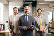 © Drazen - Happy CEO and his female colleagues stand at corporate office and look at camera.