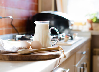 Fresh milk and eggs on wooden board in real home kitchen interior with natural light