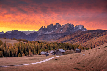 Wall Mural - incredible red sunset at fuchiade valley in italian dolomites countryside. wooden huts, orange larch
