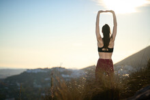 Woman With Long Hair And Red Leggings Practicing Yoga On Mountain Peak Overlooking The Sea