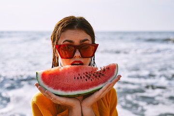 woman on the beach near the ocean eating watermelon