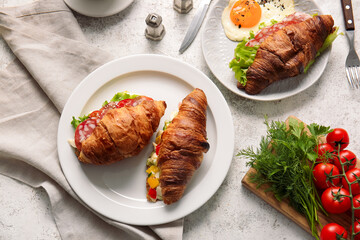 Canvas Print - Plates with delicious croissant sandwiches on light background