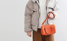 Woman In  Short Down Jacket With An Orange Handbag