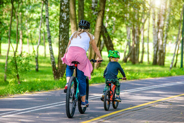 A woman and her son ride bicycles in the park
