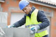© auremar - builder man holding concrete blocks for house building
