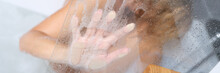 Naked Woman Sitting In Bathtub And Holding Her Hand On Misted Glass Closeup