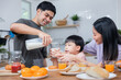 © khwanchai - Asian Thai family parents take care young boy kid eating breakfast and drink milk in morning