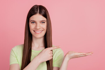 Photo portrait of girl happy positive smile pointing finger product promo isolated on pastel pink color background