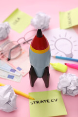 Poster - Composition with toy rocket, stationery and money on pink background, closeup. Startup concept