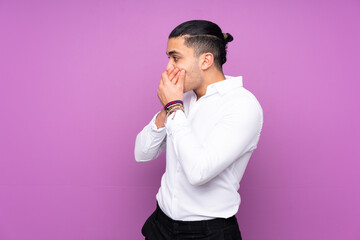 Wall Mural - Asian handsome man isolated on blue background covering mouth and looking to the side