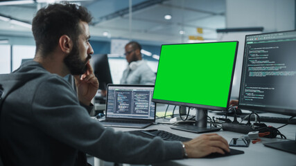 Leinwandbilder - Multi-Ethnic Office: White IT Programmer Working on Computer with Green Screen Chroma Key Display. Male Software Engineer Developing App, Program, Video Game. Terminal with Code Language.