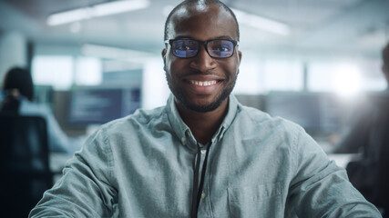 Poster - Office: Portrait of Focused IT Programmer Wearing Headphones Working on Computer, Looking at Camera and Smiling. Black Male Software Engineer Developing Innovative App, Program, Video Game.
