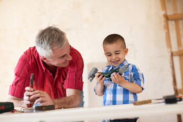 Wall Mural - Smiling grandfather and grandson working in workshop