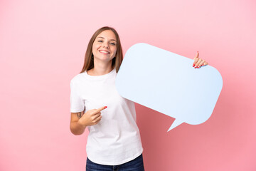 Young Lithuanian woman isolated on pink background holding an empty speech bubble and pointing it