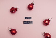 Christmas Red Bauble Balls Decoration On Pink Background. Minimal Holiday Style. Creative Flat Lay Top View Concept. Merry Christmas Spelled With Sticker Label.