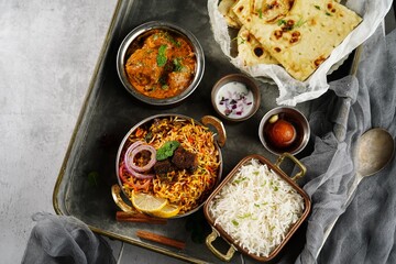 Wall Mural - Indian meal thali - mutton biryani, raita, malai kofta, basmati rice, butter naan and gulab jamun served on a tray