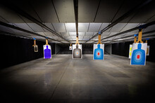 Professional Indoor Target Shooting Range Looking Down Range At Targets. Assorted Targets Have Bullet Holes.