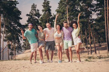 Wall Mural - Photo of pretty sweet young six friends wear casual clothes smiling hugging walking showing v-signs outside countryside