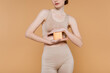 © LIGHTFIELD STUDIOS - Cropped view of young woman in top holding cosmetic cream isolated on beige