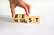 Best or worst symbol. Businessman turns wooden cubes and changes the word best to worst. Beautiful white table, white background, copy space. Business and best or worst concept.