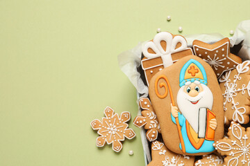 Wall Mural - Tasty gingerbread cookies on light green background, flat lay. St. Nicholas Day celebration