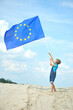 © Jacek - The child runs with the European flag against the background of a blue sky.
