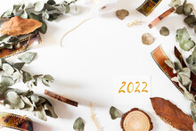 Card Hand Writen 2022. Frame With Old-fashioned Camera Films, Dried Branches Of Eucalyptus Leaves, And Wood Pieces On White Background. Flat Lay, Overhead View, Top View. Vintage Composition.