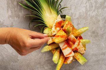 Wall Mural - Cucumber, jicama and pineapple with chili powder and chamoy sauce on gray background. Mexican snack