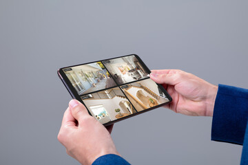 Canvas Print - Hands of caucasian man holding tablet with view of home from security cameras on screen