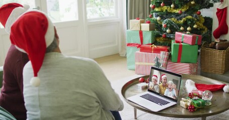 Wall Mural - Diverse senior female friends using laptop for christmas video call with happy family on screen