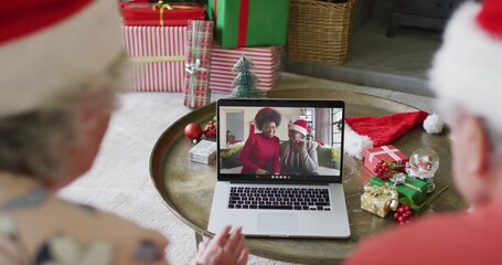 Canvas Print - Senior caucasian couple using laptop for christmas video call with happy family on screen