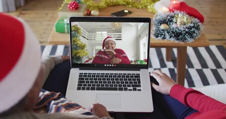 Wall Mural - African american mother and daughter using laptop for christmas video call with woman on screen