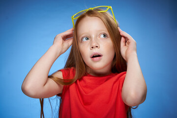 Wall Mural - cute red-haired girl in red t-shirt emotions blue background