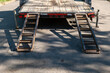 © scandamerican - Ramps attached to a truck for loading a vehicle of machine onto the flatbed trailer as it sits parked on the asphalt of the street.