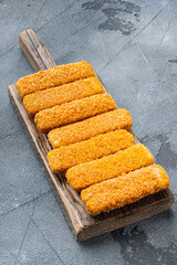 Wall Mural - Chunky breaded frozen fish fingers, on wooden cutting board, on gray background