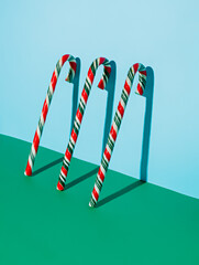 Canvas Print - Red and Green Christmas candy canes leaning on the bright blue wall. Festive candies and sweet food. Creative Xmas and New Year creative concept. December winter holidays idea.