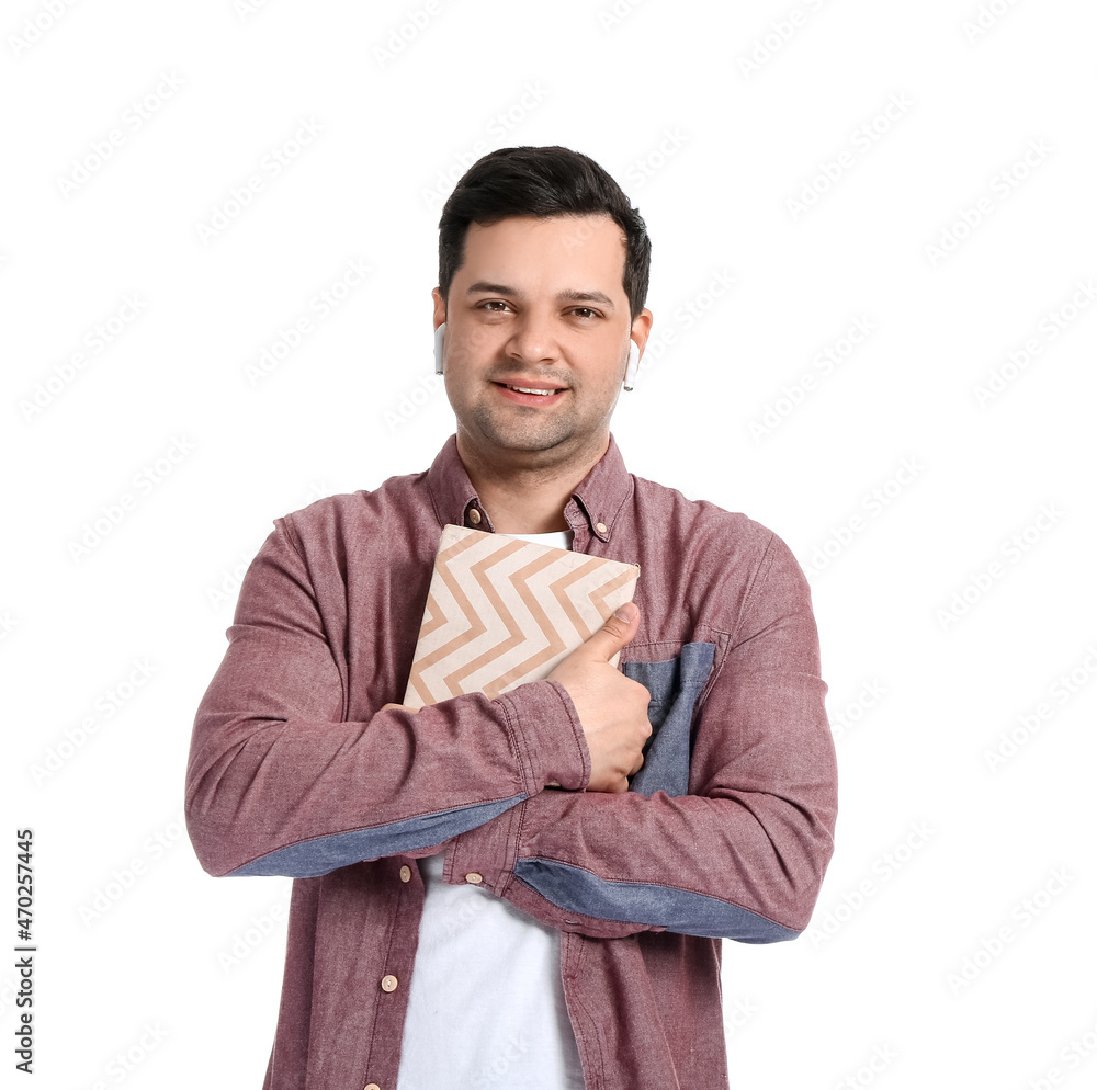 Young man with book and earphones on white background