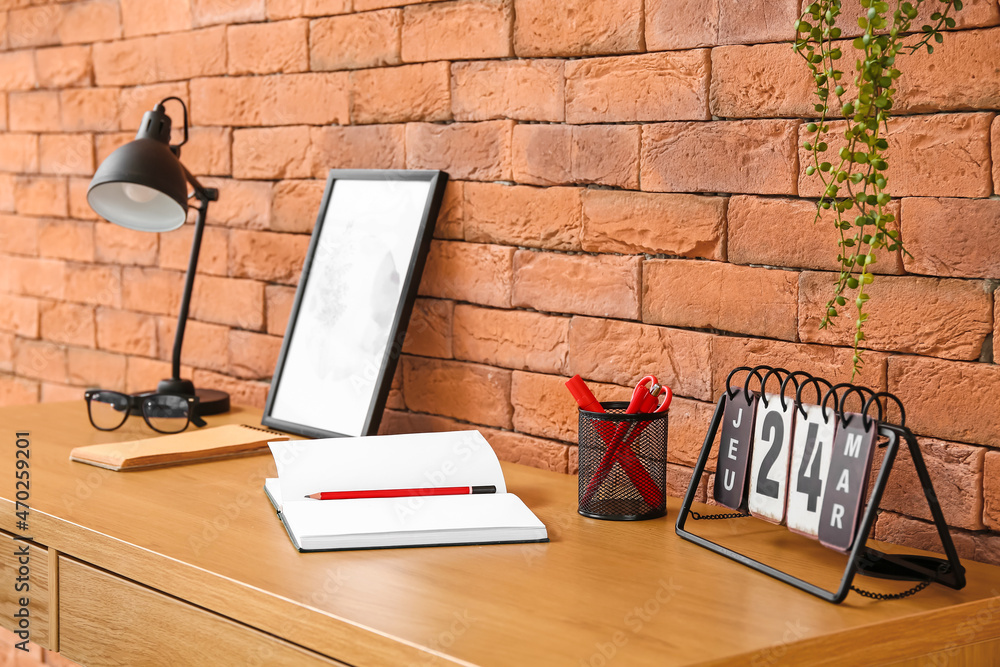 Comfortable workplace near brown brick wall in interior of room
