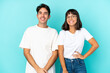 © luismolinero - Young mixed race couple isolated on blue background posing with arms at hip and smiling