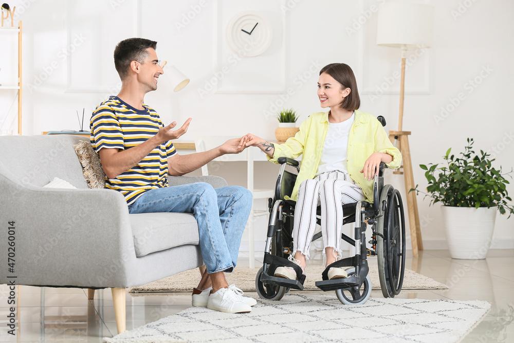 Young woman in wheelchair and her husband at home