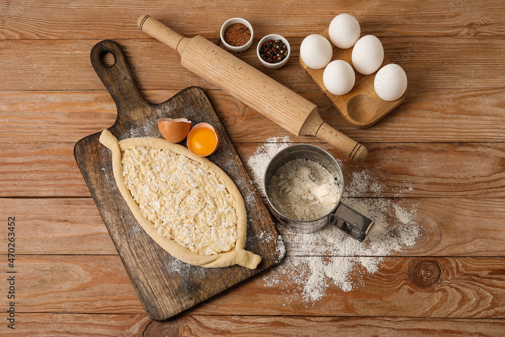 Homemade Ajarian khachapuri preparing for baking on wooden background