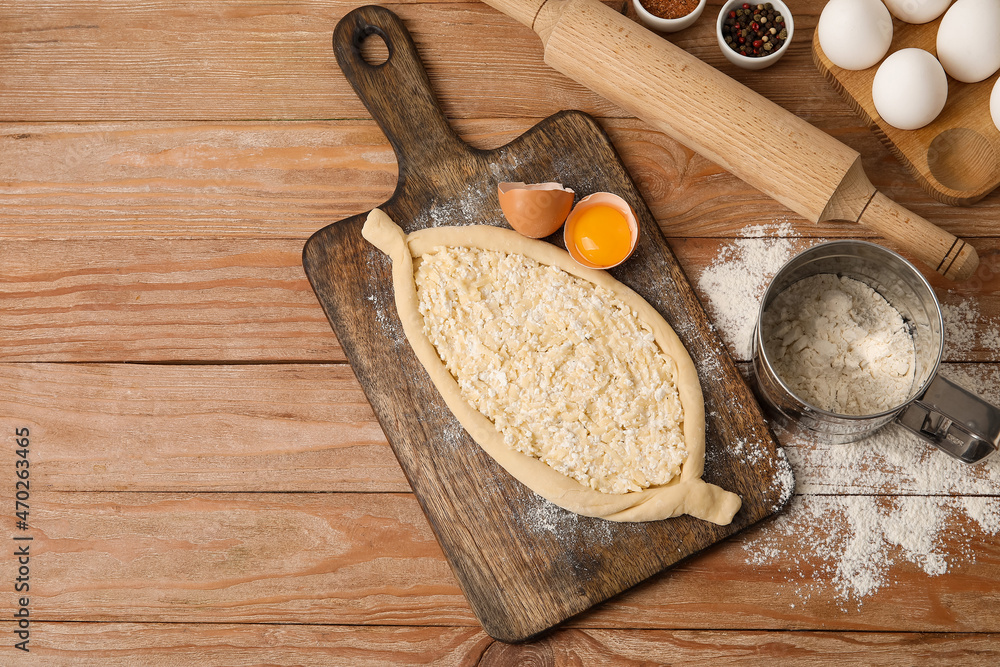 Homemade Ajarian khachapuri preparing for baking on wooden background