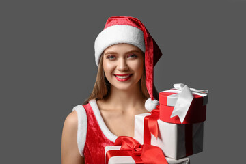 Wall Mural - Beautiful young woman in Santa costume and with Christmas gifts on dark background