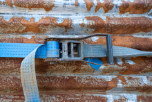 A Blue Rachet Strap Wrapped Around A Rusty Corrugated Iron Metal Sheet
