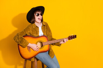 Wall Mural - Photo of sweet adorable woman dressed cowboy clothes cap singing playing guitar empty space isolated yellow color background