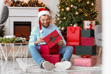 Canvas Print - Handsome man opening Christmas gifts at home