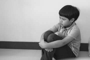 Depressed Boy Sitting on the Floor in the house on black and white tone.