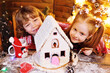 © Evgeniy Kalinovskiy - small children-a boy and a girl prepare a gingerbread house, smile and have fun on the background of Christmas decor
