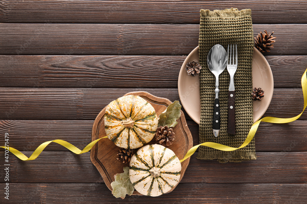 Composition with table setting, pumpkin and autumn leaves on dark wooden background