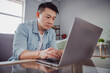 © Tetiana - Photo of focused confident business man japanese man sit couch programming code wear casual shirt in home indoors